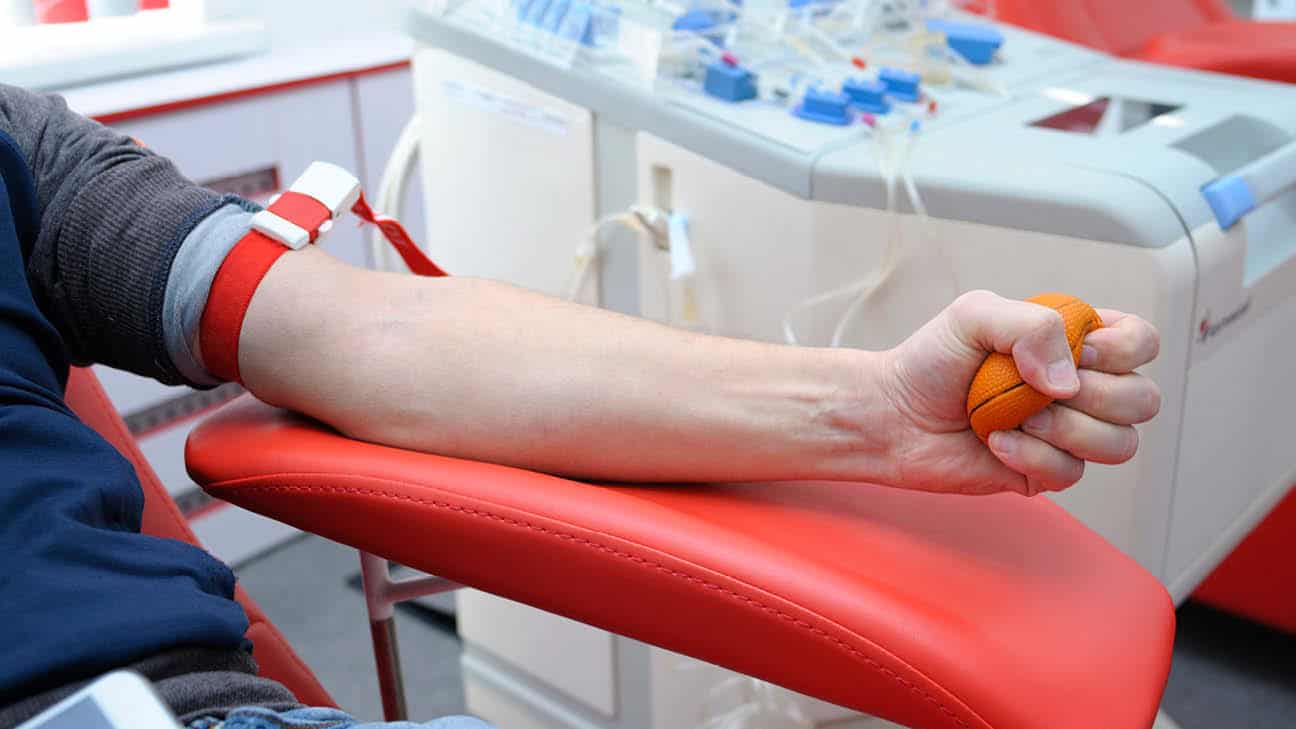 A person getting their blood drawn while squeezing a foam ball.