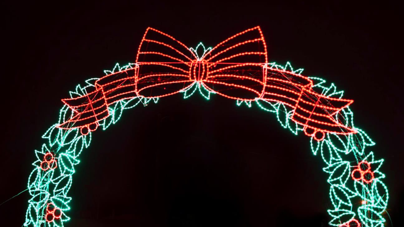 A Christmas light display in the shape of wreath with a red bow