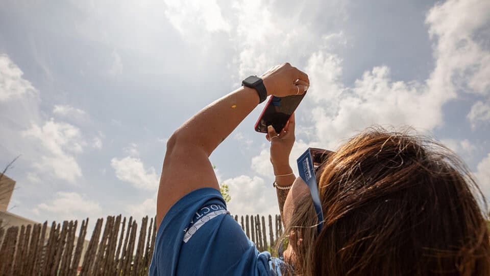 A girl takes a photo of the eclipse with her cell phone camera