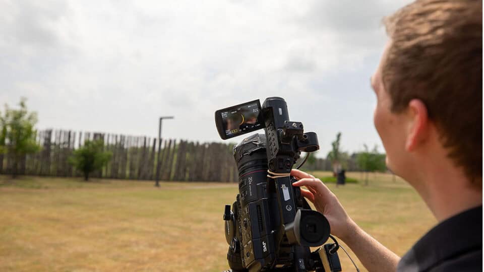 The crescent sun can be seen in the camera viewfinder of a news camera