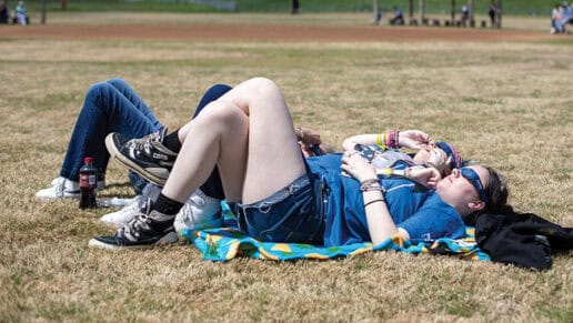 Three women lay on a blanket and watch the eclipse