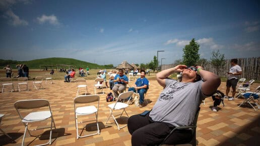A woman looks at the eclipse wearing her eclipse glasses