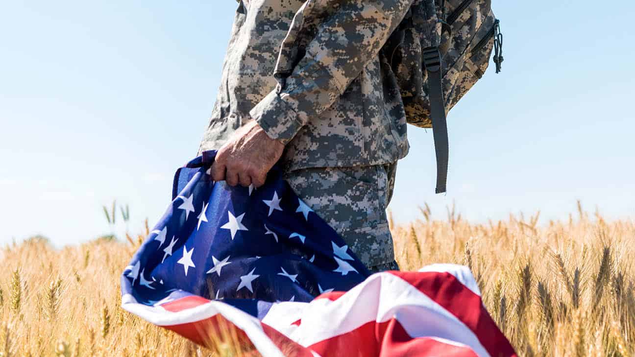 Army veteran with backpack carrying a US flag