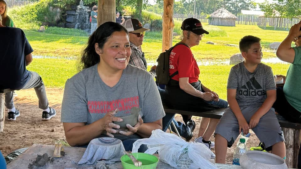 A woman smiles as she does pottery