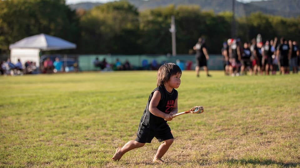 Little boy plays stickball at the Labor Day Festival.