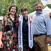 Three people, a mom, an adult child, and a dad, pose for a photo.