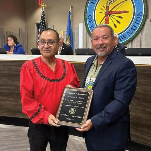 An older man in a red traditional Choctaw shirt poses for a photo with council member Anthony Dillard.