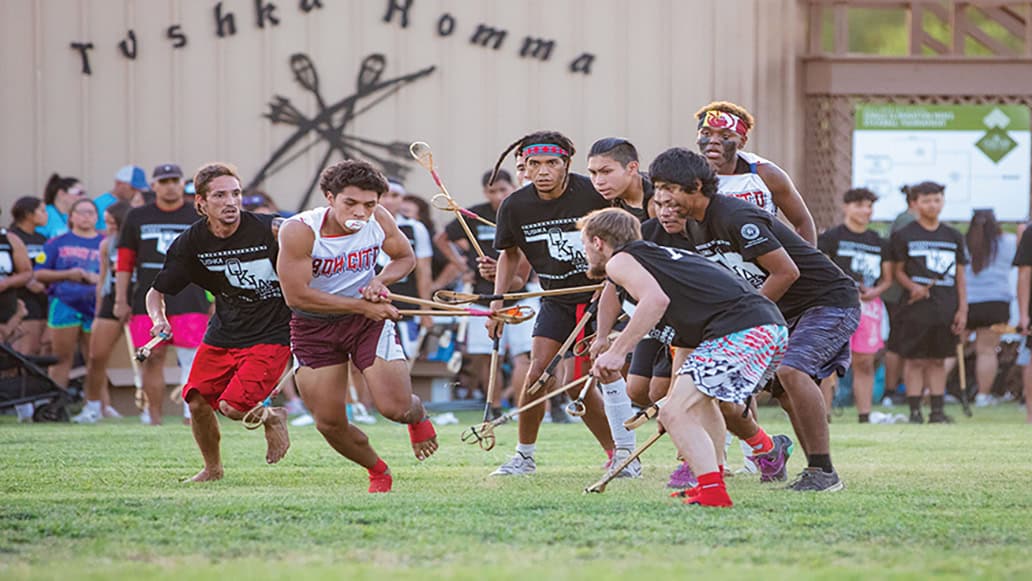 A man runs with the ball in his sticks.