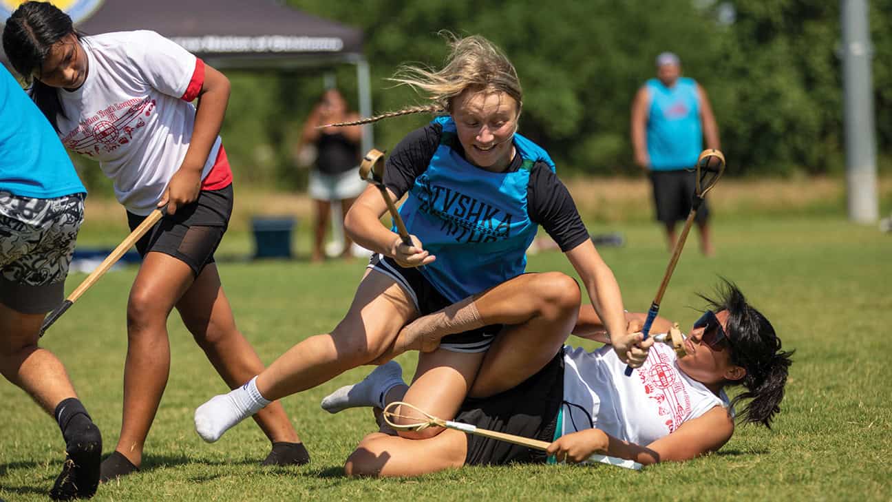 A women tackles another women during a game of stickball.
