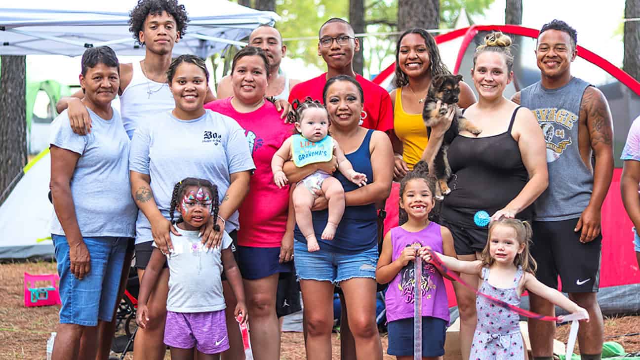 A large family stands in front of camping tents during the Labor Day festival of 2023.