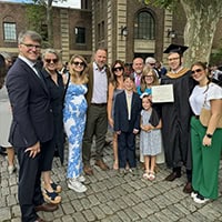 Group of happy people standing together, proudly displaying a diploma for a photo.