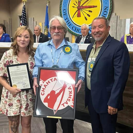 A woman, an older man and council member Anthony Dillard pose for a photo. The man in the middle holds a plaque.