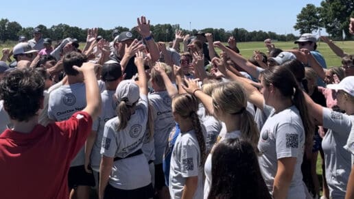 A group of students with their hands in the air gather together at a CNO Summer Camp