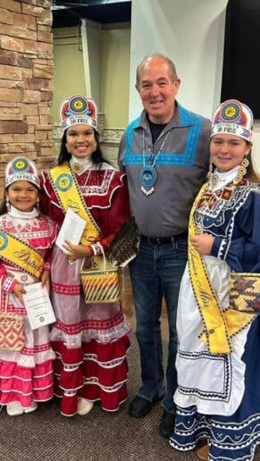 District 9 Royalty, dressed in their tribal regalia, pose for a photo with James Dry