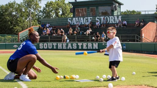 A coach pitches a ball to a young camper at the N7 Diamond Experience.