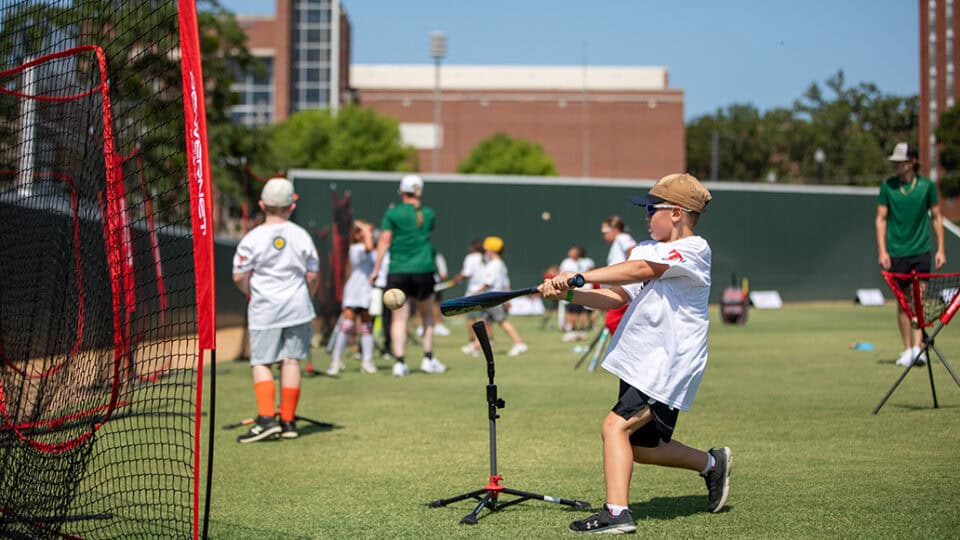 A baseball player swings at a ball on a practice tee at the N7 Diamond Experience.