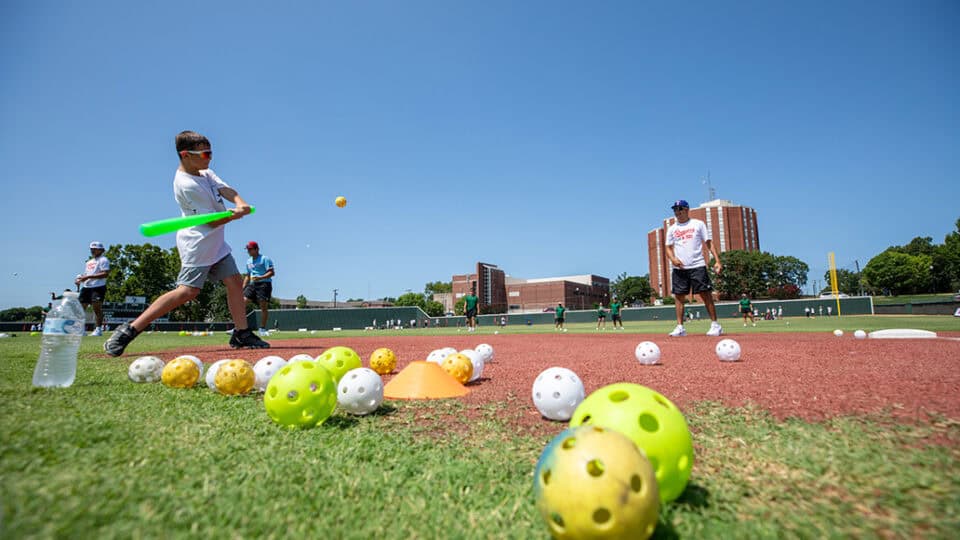 An attendee swings at a practice ball thrown by a coach at the N7 Diamond Experience.