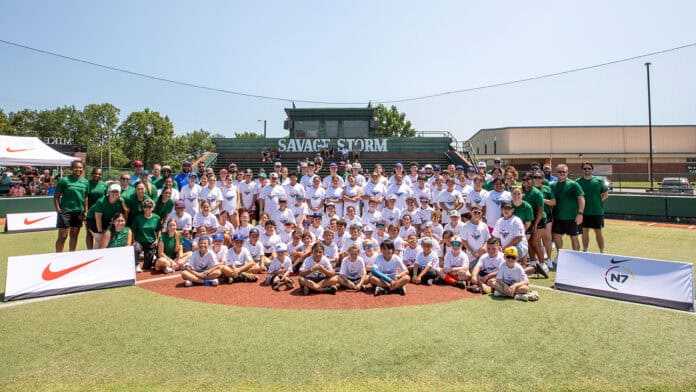 A large group of students wearing white shirts are joined by coaches in green at the N7 Diamond Experience.