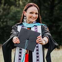 Women smiles while holding graduation cap