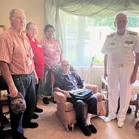 A group of people surround Walcott Jones sitting in a recliner.