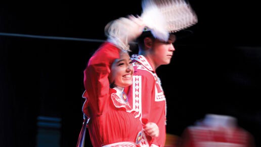 A princess contestant waves to the crowd holding a fan.