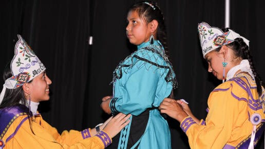 A princess contestant is helped with her regalia.