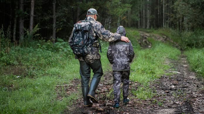 Dad and son walking while hunting and fishing