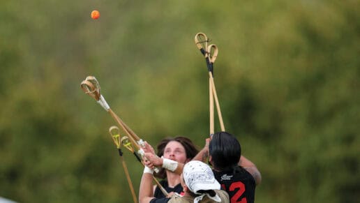 Three stickball players jump in the air to grab a falling stickball.