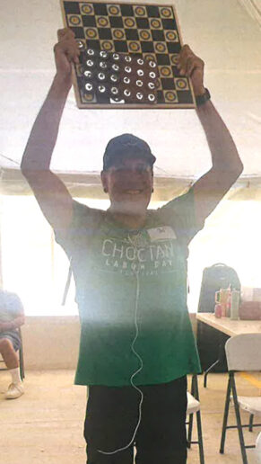 a man in a green shirt holds a checkerboard over his head.