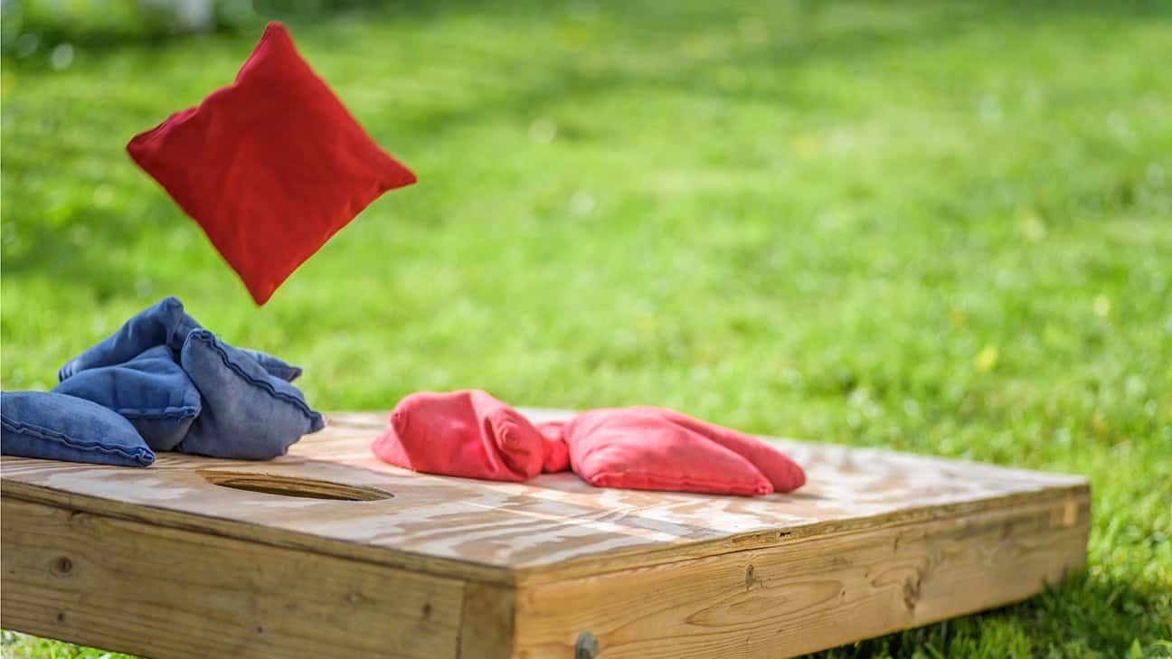 A cornhole bag flies through the air towards the board.