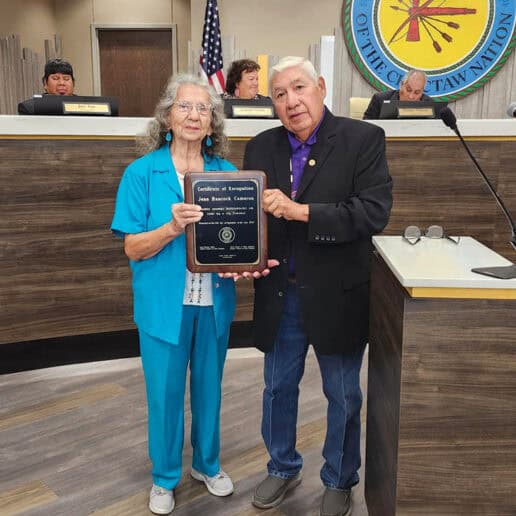 A woman in a bright blue pantsuit receives a plaque from Councilman James Fraizer.