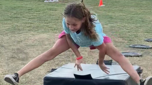 A girl jumps over a box.