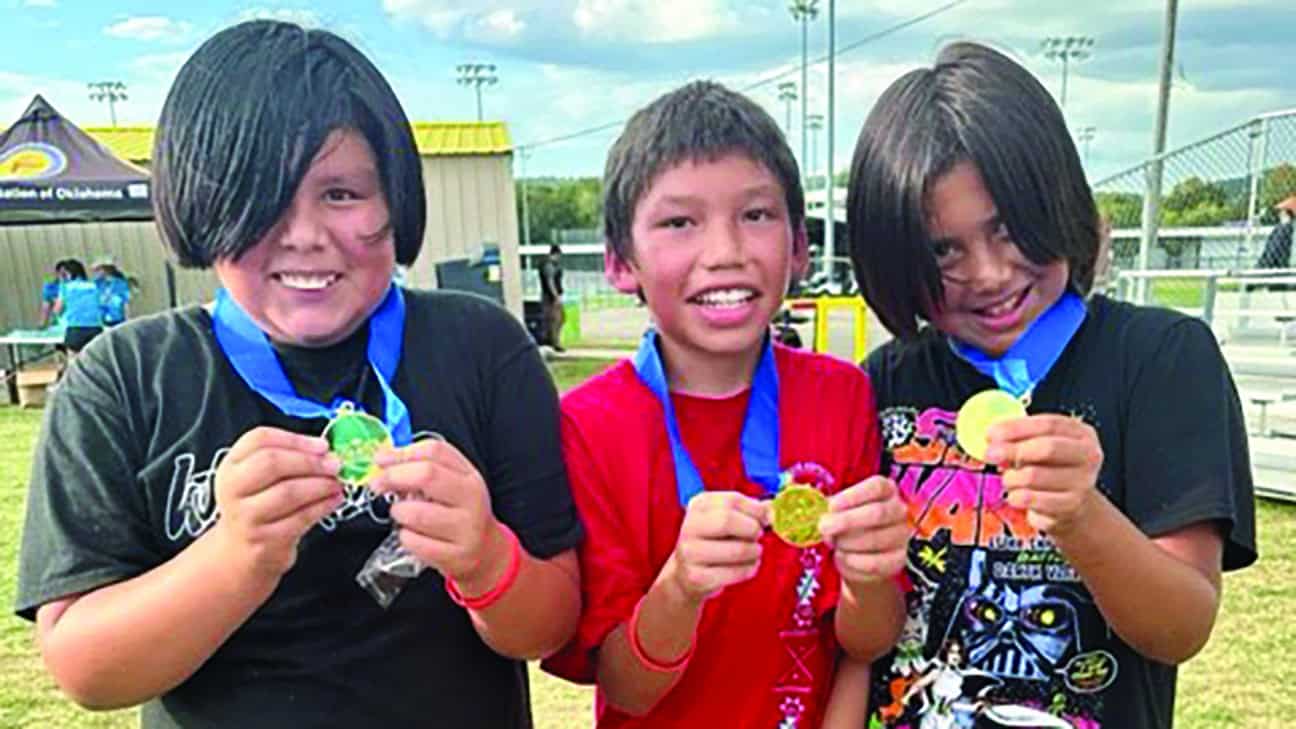 Three kids pose with their medals.