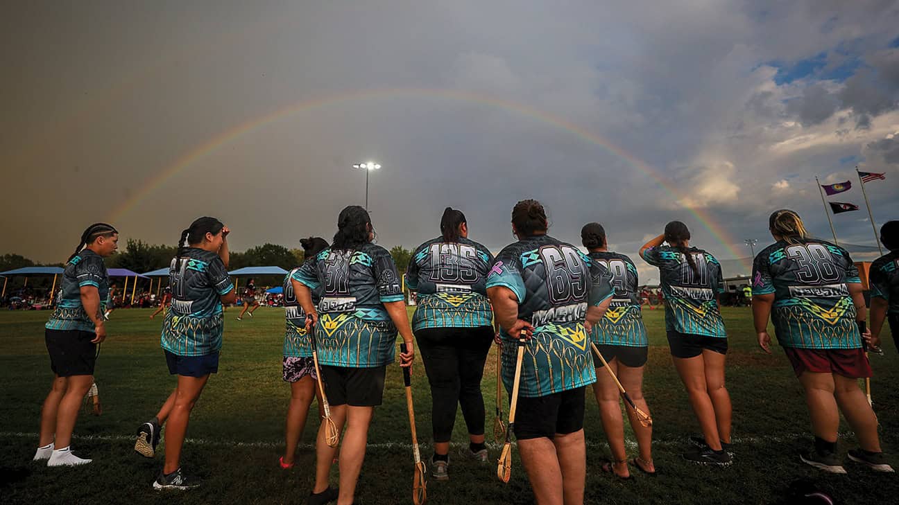 Players from Rogue stickball team watch their teammates compete after a rain shower.