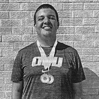 A young man wearing an ORU shirt smiles as he shows off his medals.