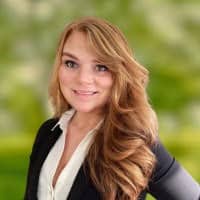 Young woman poses for a photo in front of a blurry green background.