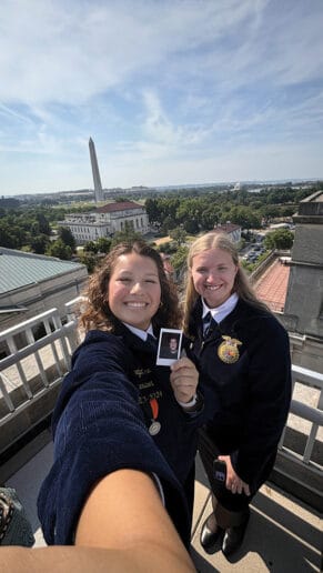 Two young women pose for a photo with the Washington Monument in the background.