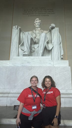 Two young women pose for a photo with the Lincoln Memorial in the background.