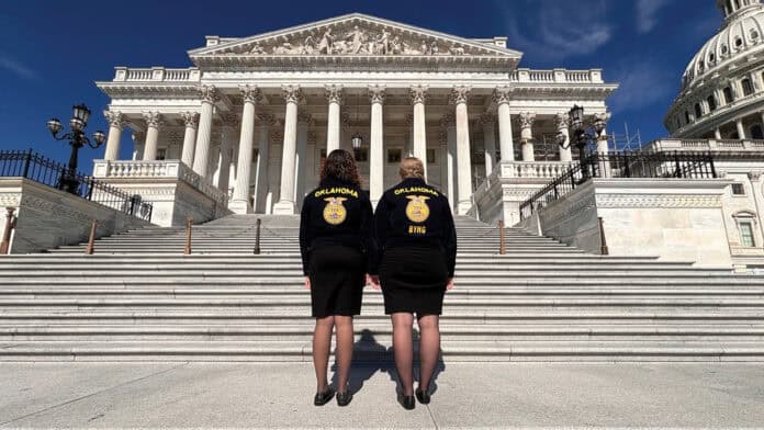 Two women face the capital building wearing Future Farmers of America jackets.