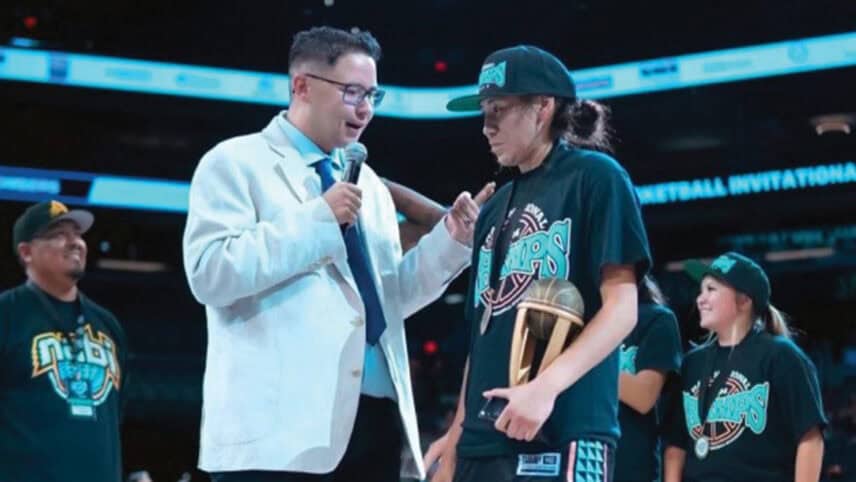 Tyler jones speaks to a basketball player on the court.