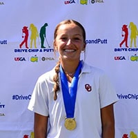 A young woman, Harlow Gregory, poses for a picture with a medal arund her neck.