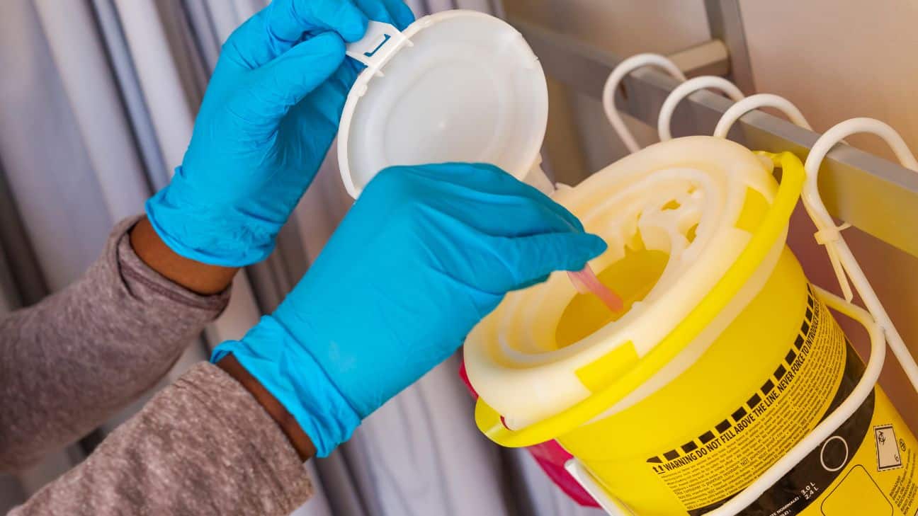 Healthcare worker with gloves disposing of biohazard.