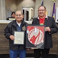 A man presents and award to the man on the left.