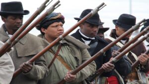 Caleb Sullivan participates in a musket firing demonstration for park visitors. He is wearing a turban and French frock coat—both were worn by Choctaw men in the early 1800’s