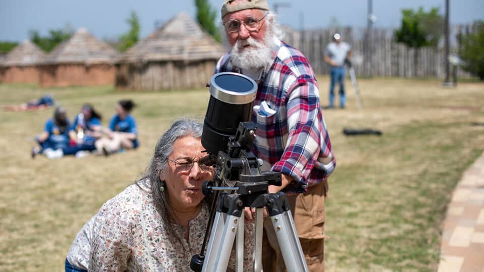 A woman looks through a telescope fitted with a special eclipse lens.