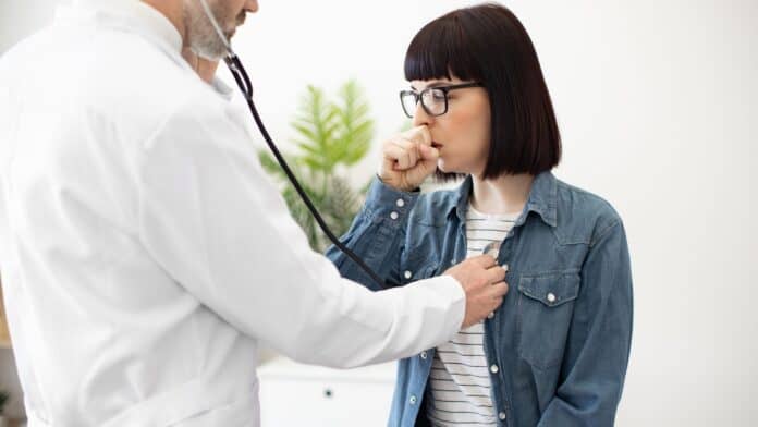 Doctor listening to a woman's chest for respiratory issues.