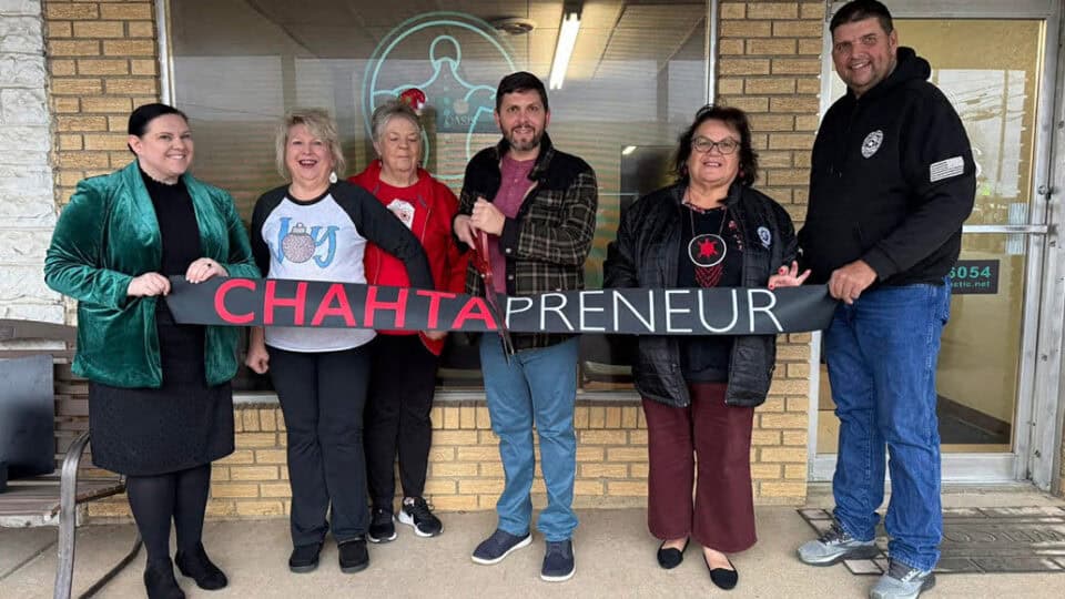 people stand in front of a business holding a ribbon that says Chahtapreneur and a pair of oversized scissors.