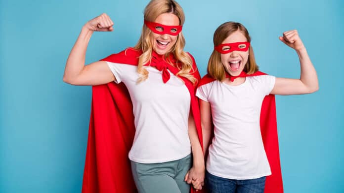 Mother and daughter wearing a superhero cape and mask flexing their muscles.