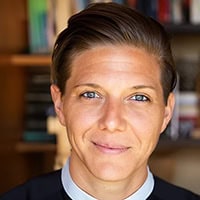 A young woman with short hair, wearing a clerical collar.