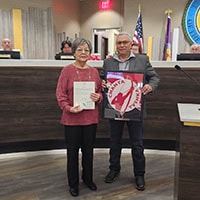 Older woman holds up plaque next to tribal council member, Eddie Bohanan.